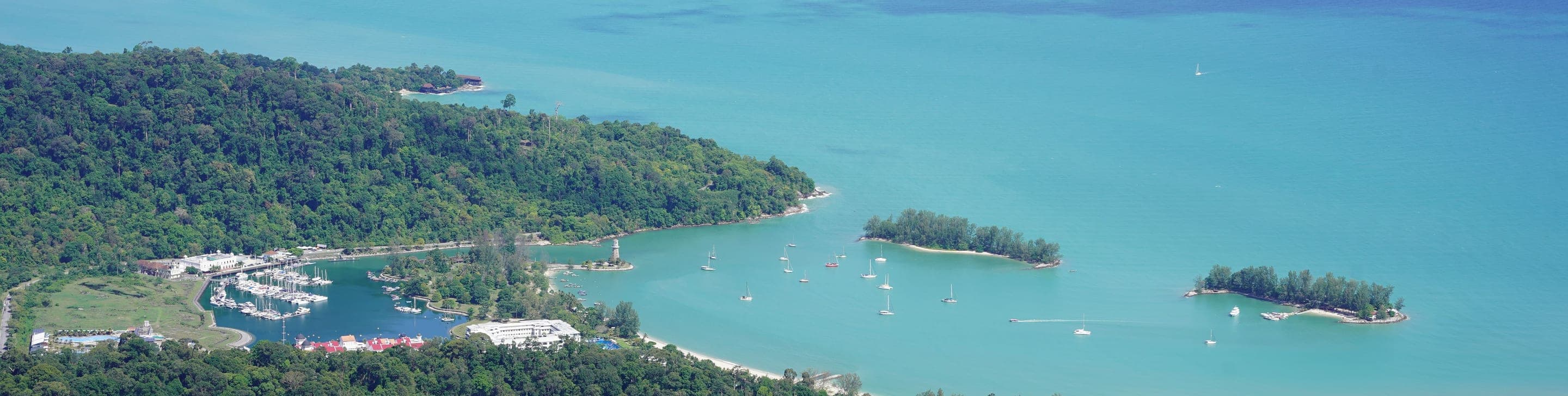 Aerial view of a forested headland, marina and turquoise bay in Malaysia